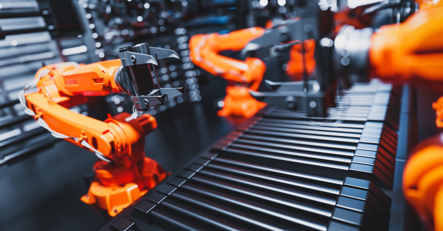 Orange robotic arms working along a conveyor belt in a factory
